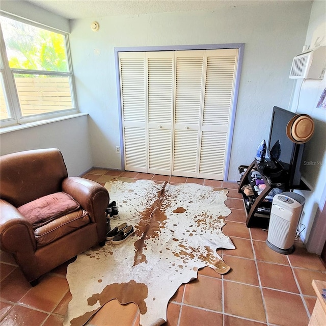 living area featuring tile flooring and a wall mounted air conditioner