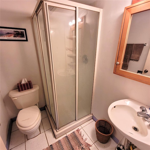 bathroom featuring a shower with shower door, toilet, tile floors, and sink