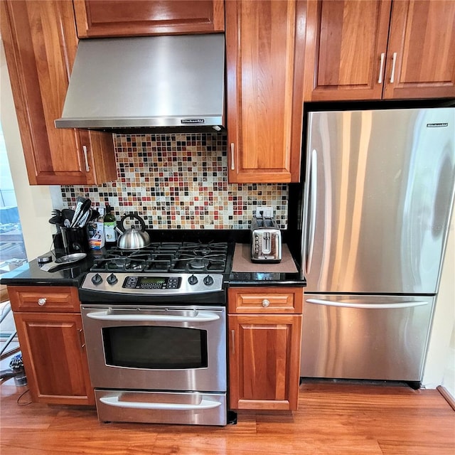 kitchen featuring light hardwood / wood-style floors, appliances with stainless steel finishes, wall chimney exhaust hood, and tasteful backsplash