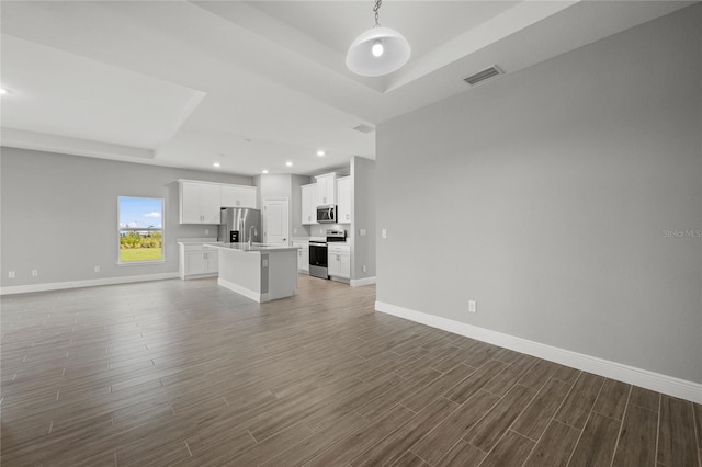 unfurnished living room with a tray ceiling and dark wood-type flooring