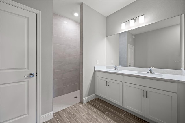 bathroom with double sink vanity and a tile shower