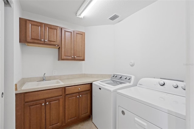 washroom with a textured ceiling, cabinets, sink, and separate washer and dryer