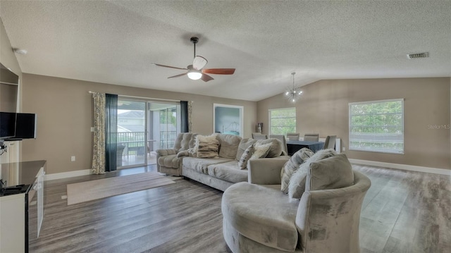 living room with ceiling fan with notable chandelier, lofted ceiling, a wealth of natural light, and light hardwood / wood-style floors