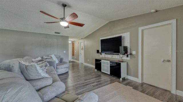 living room with ceiling fan, vaulted ceiling, and dark wood-type flooring