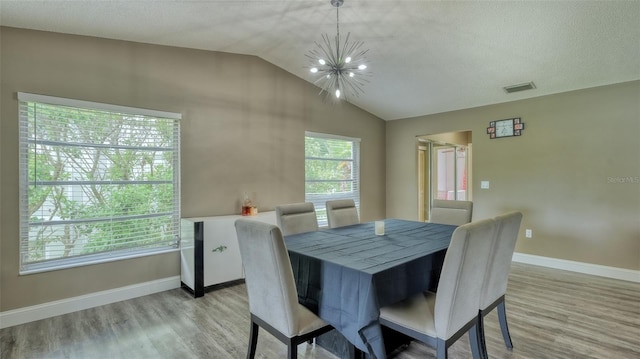 dining room featuring light hardwood / wood-style flooring, vaulted ceiling, and a notable chandelier