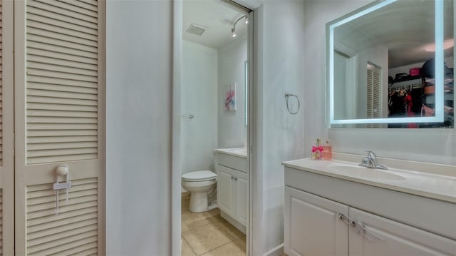 bathroom with toilet, tile flooring, and vanity