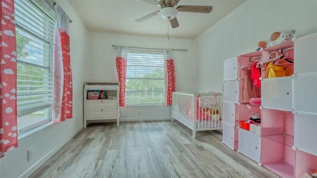 unfurnished bedroom with a crib, light hardwood / wood-style floors, and ceiling fan