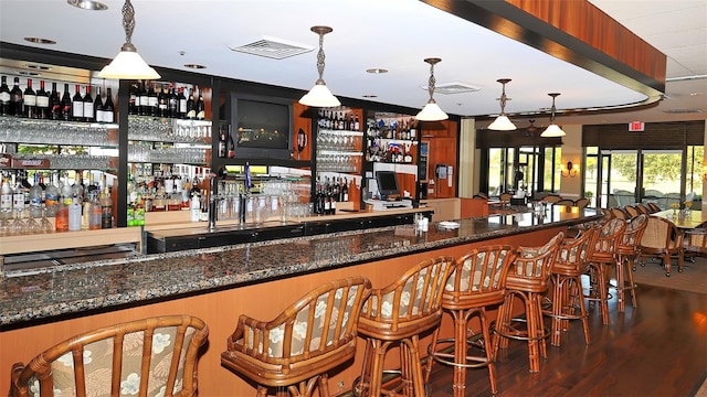 bar featuring dark stone countertops and pendant lighting