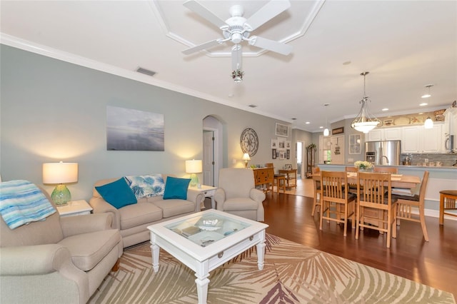 living room featuring dark hardwood / wood-style floors, ceiling fan, and ornamental molding