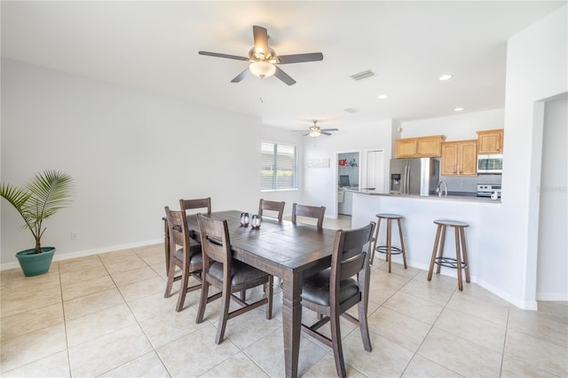 tiled dining area featuring ceiling fan and sink