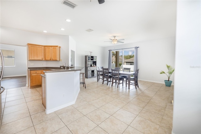 kitchen featuring a kitchen bar, light tile floors, ceiling fan, and sink