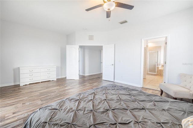 unfurnished bedroom featuring ceiling fan, ensuite bath, and light tile floors