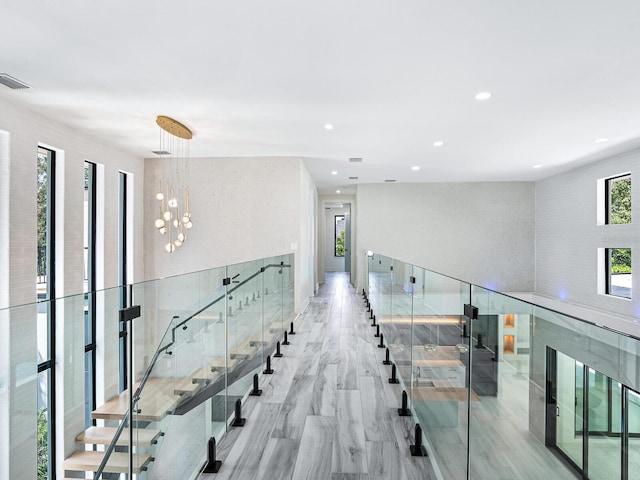 hall with a chandelier and light wood-type flooring