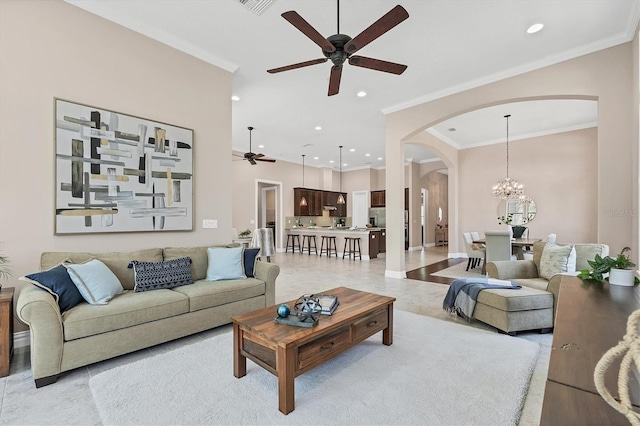 living room featuring ornamental molding, light tile floors, and ceiling fan with notable chandelier