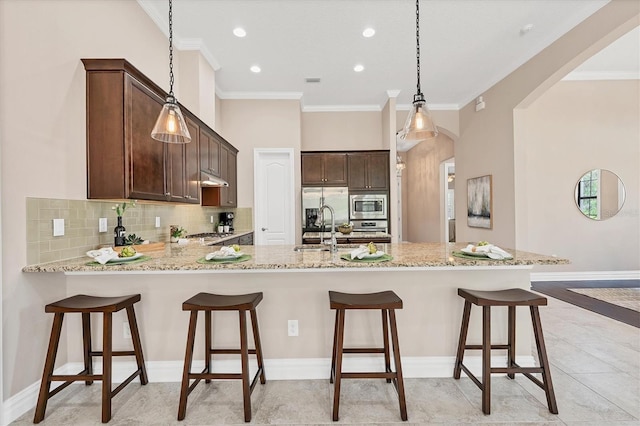 kitchen with light tile floors, a kitchen breakfast bar, stainless steel appliances, and hanging light fixtures