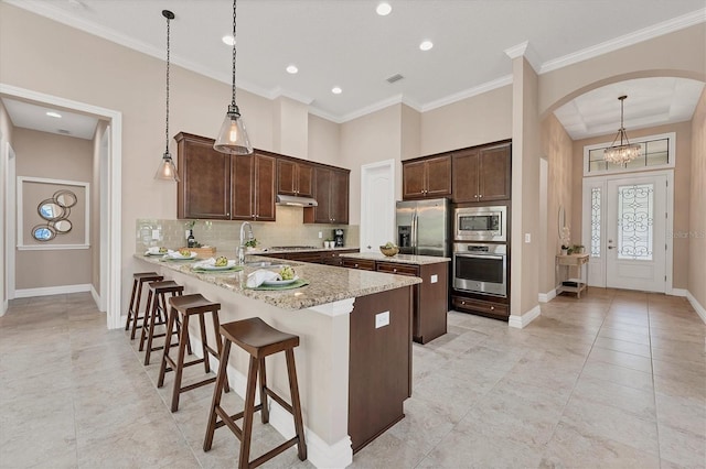 kitchen with appliances with stainless steel finishes, backsplash, kitchen peninsula, and decorative light fixtures