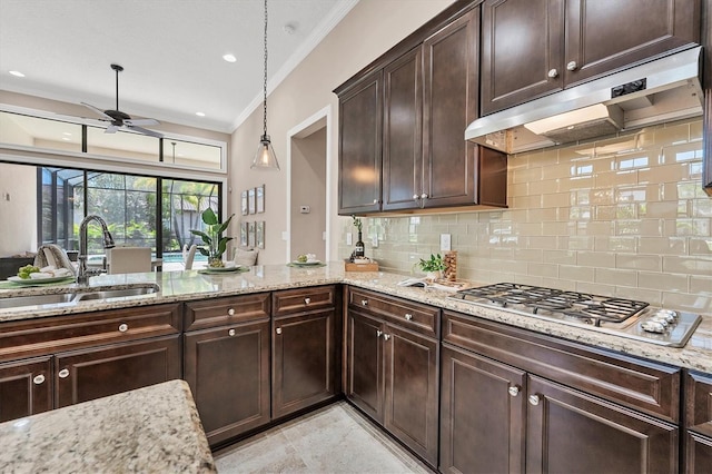 kitchen featuring decorative light fixtures, backsplash, sink, and light stone countertops