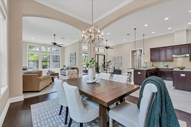 dining room featuring crown molding, sink, dark wood-type flooring, and ceiling fan with notable chandelier