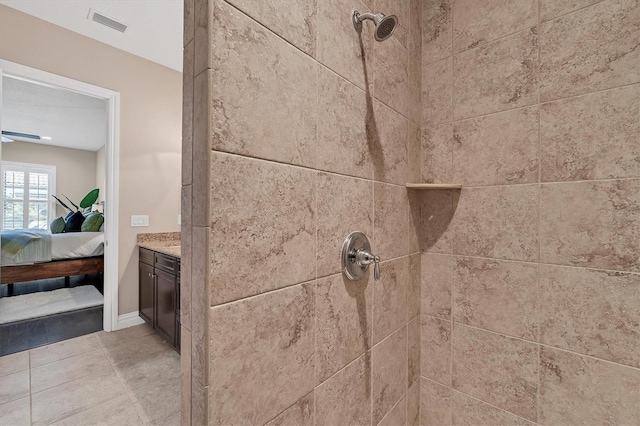 details featuring light tile flooring, tiled shower, and vanity