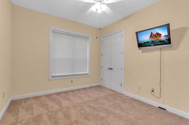 unfurnished bedroom with a closet, light colored carpet, and ceiling fan