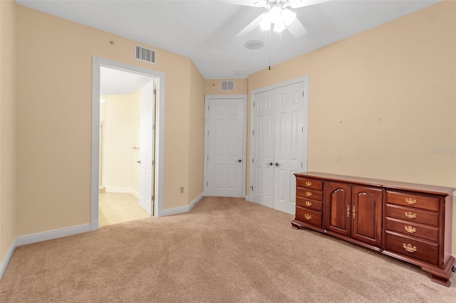 unfurnished bedroom featuring ensuite bath, ceiling fan, and light carpet