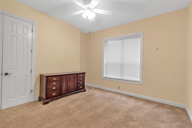 empty room with a wealth of natural light, light carpet, and ceiling fan