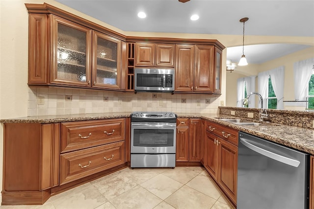 kitchen with decorative backsplash, appliances with stainless steel finishes, dark stone counters, sink, and decorative light fixtures