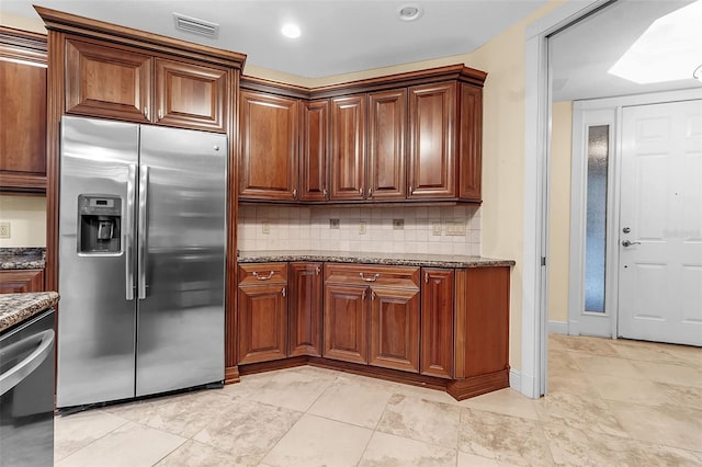 kitchen featuring decorative backsplash, stainless steel refrigerator with ice dispenser, and dark stone counters