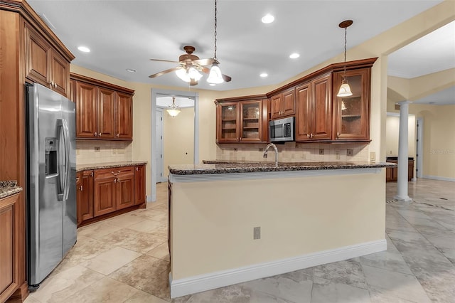 kitchen featuring pendant lighting, decorative backsplash, stainless steel appliances, and dark stone counters