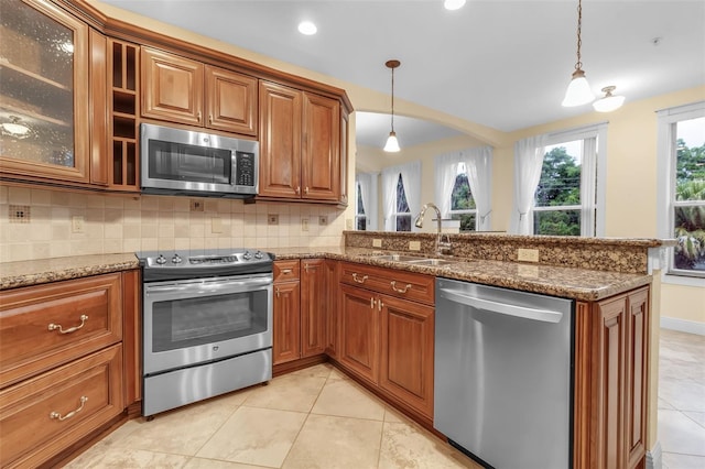 kitchen with stone countertops, stainless steel appliances, a wealth of natural light, and sink