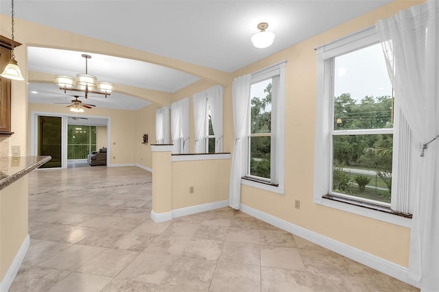 kitchen featuring light stone countertops, ceiling fan with notable chandelier, decorative light fixtures, and ornamental molding