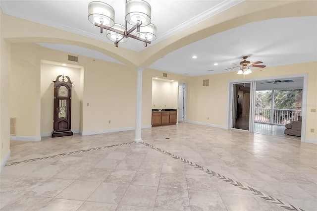 unfurnished living room featuring ceiling fan with notable chandelier, ornate columns, crown molding, and sink