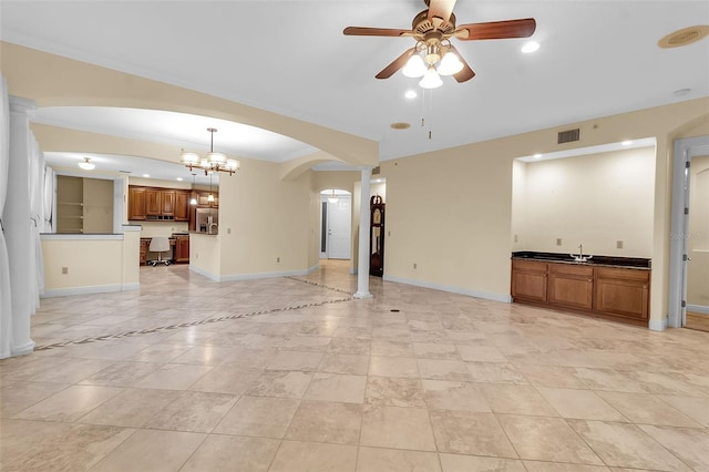 unfurnished living room featuring sink, ceiling fan with notable chandelier, and ornamental molding