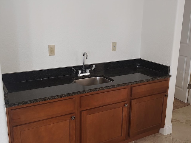 kitchen with light tile patterned floors, dark stone counters, and sink