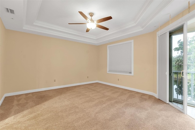 carpeted empty room featuring a tray ceiling, ceiling fan, and crown molding