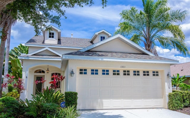 view of front of house featuring roof with shingles, driveway, an attached garage, and stucco siding