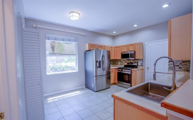 kitchen featuring decorative backsplash, stainless steel appliances, light brown cabinetry, a sink, and light tile patterned flooring