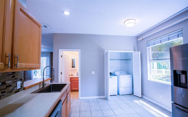 kitchen with light tile patterned floors, a sink, visible vents, stainless steel refrigerator with ice dispenser, and washing machine and clothes dryer