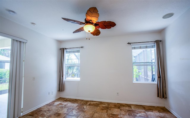 unfurnished room featuring ceiling fan and baseboards