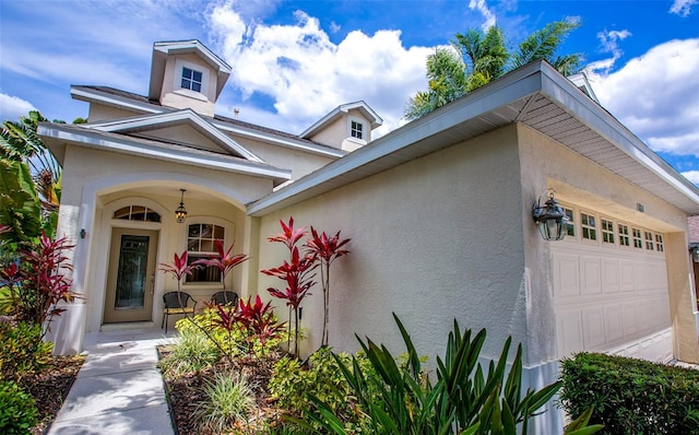 view of front of house with an attached garage, a porch, and stucco siding