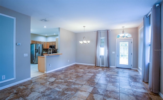 foyer entrance with an inviting chandelier, baseboards, and visible vents