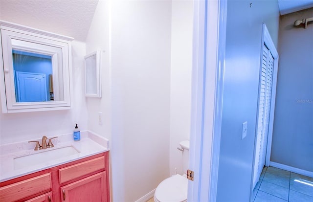 bathroom featuring toilet, a textured ceiling, vanity, baseboards, and tile patterned floors