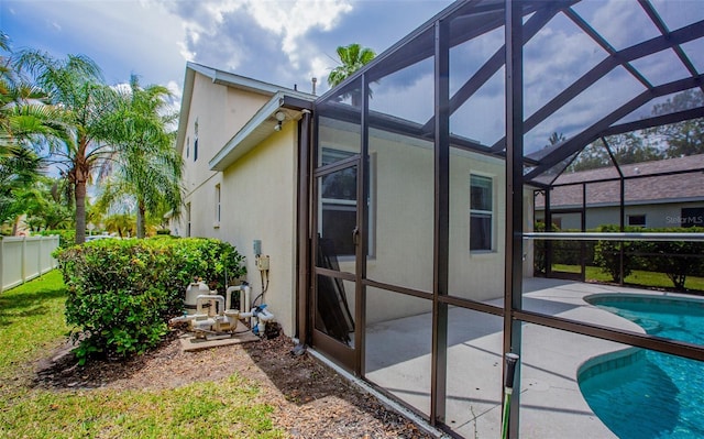 view of property exterior featuring a lanai, a patio, fence, and stucco siding