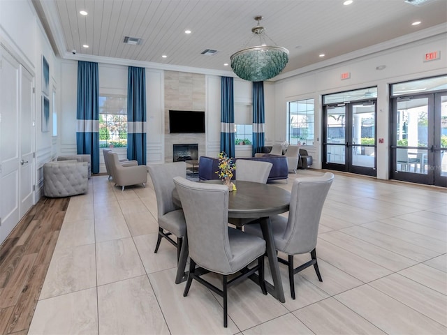 dining space with a tile fireplace, ornamental molding, wooden ceiling, and french doors