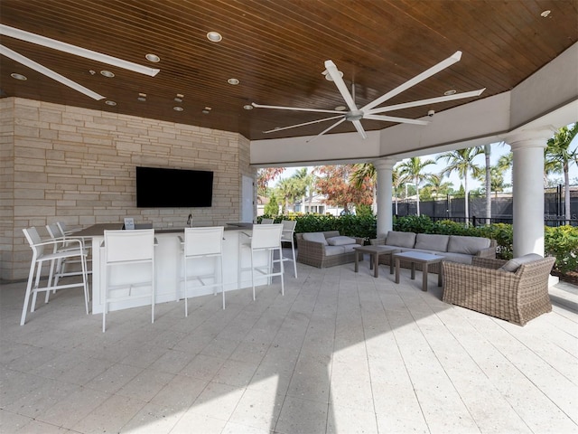 view of patio with an outdoor living space, ceiling fan, and a bar