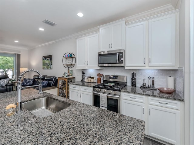 kitchen with white cabinetry, stainless steel appliances, sink, and backsplash