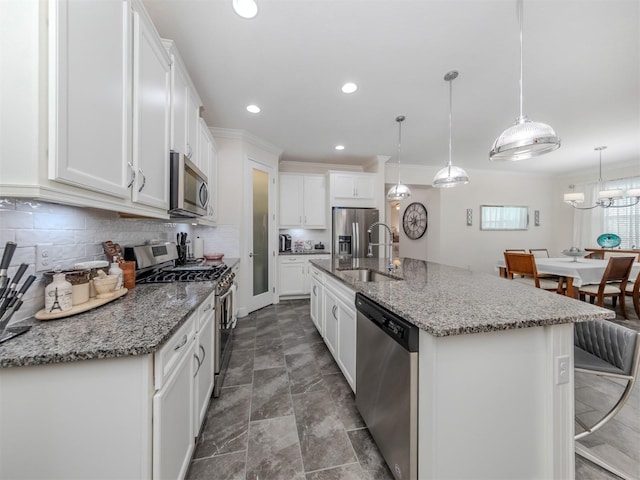 kitchen featuring pendant lighting, stainless steel appliances, a kitchen island with sink, and white cabinets