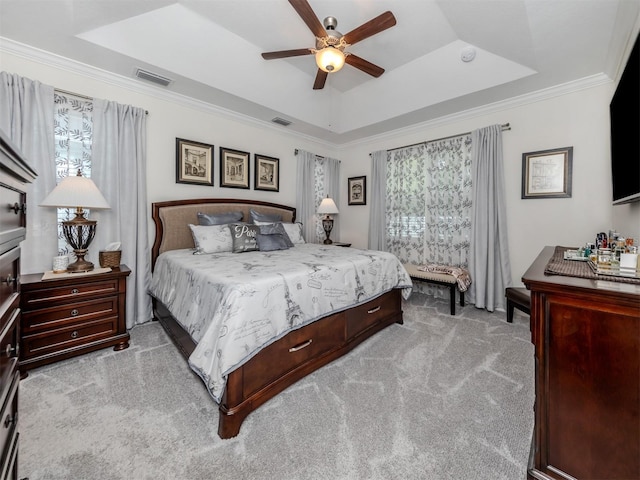 bedroom with a tray ceiling, ornamental molding, light colored carpet, and ceiling fan