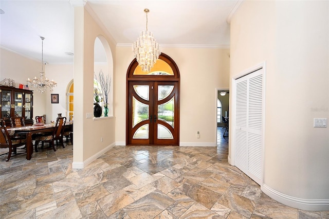 foyer entrance featuring a chandelier, ornamental molding, light tile floors, and french doors