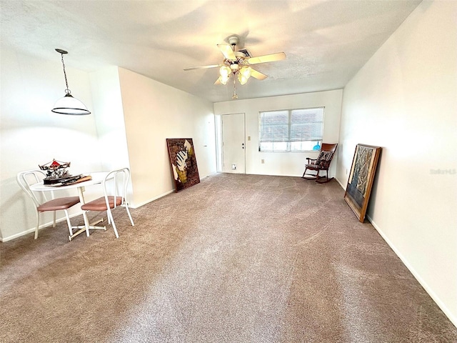 living area featuring dark carpet and ceiling fan